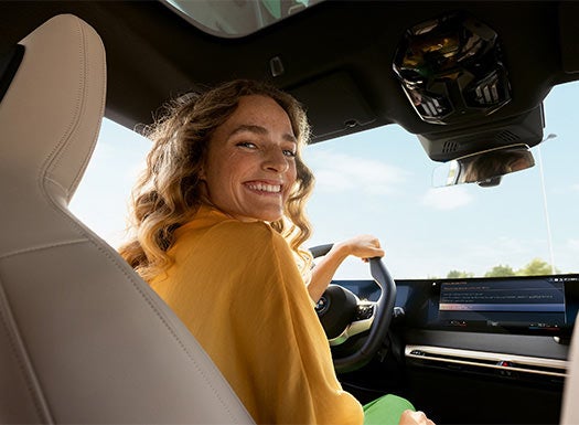 Woman sitting in the driver’s seat of a BMW vehicle with display screen visible.